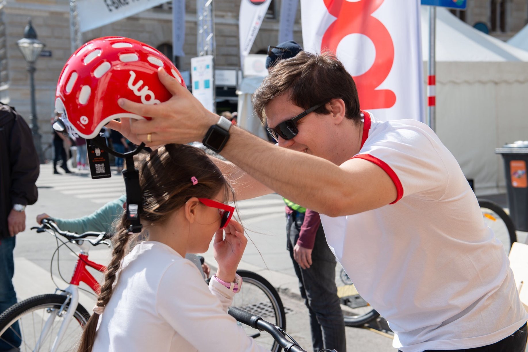 Bruno placing a helmet on a little lady ready for an adventure on her bike